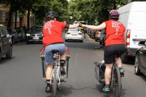 Two female riders on e-cargo bikes doing the two fisted salute