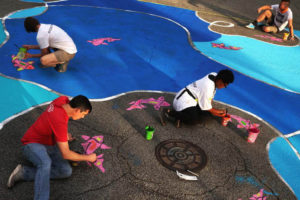 As part of an initiative by the Bloomberg Philanthropies Foundation, artists paint the asphalt of a road junction