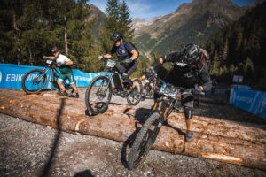 Ebike riders cross an obstacle made of several tree trunks at the E-Bike World Championship for Everyone.